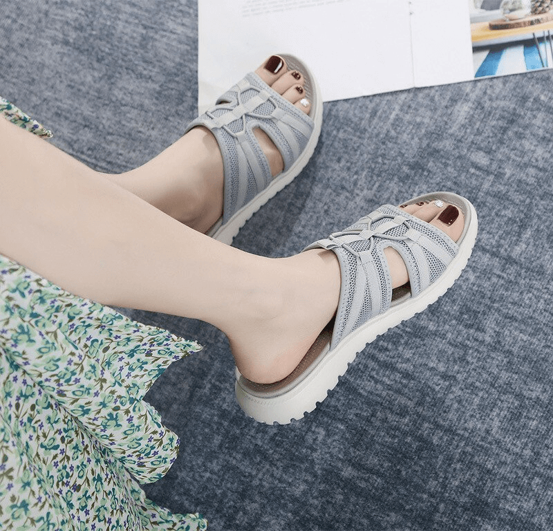 Woman wearing lightweight waterproof athletic soft flat slippers, light grey color, ideal for comfort and style on a casual day.